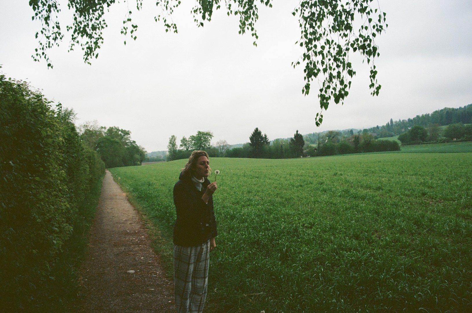 Jess blowing a dandilion on a cold, gloomy day in Switzerland. 